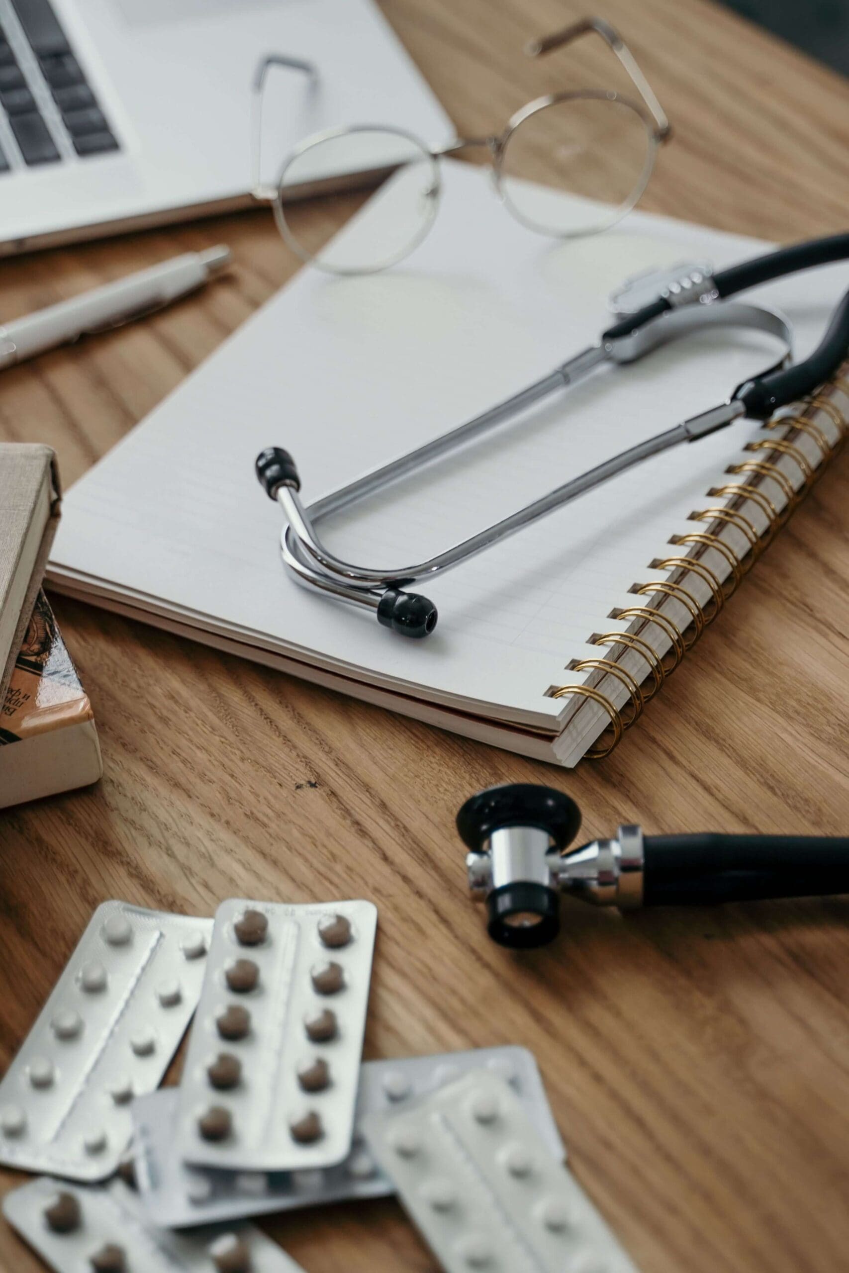 Desk of doctor with stethoscope, note pad, medication
